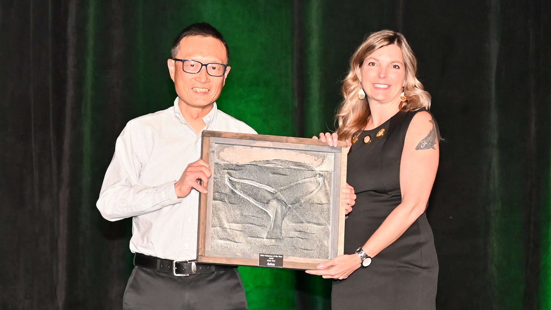 A man and a woman stand on stage holding an award