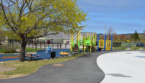 Bannerman Park playground with colourful metal and plastic equipment, in the background is the Bannerman Park pool and pool house