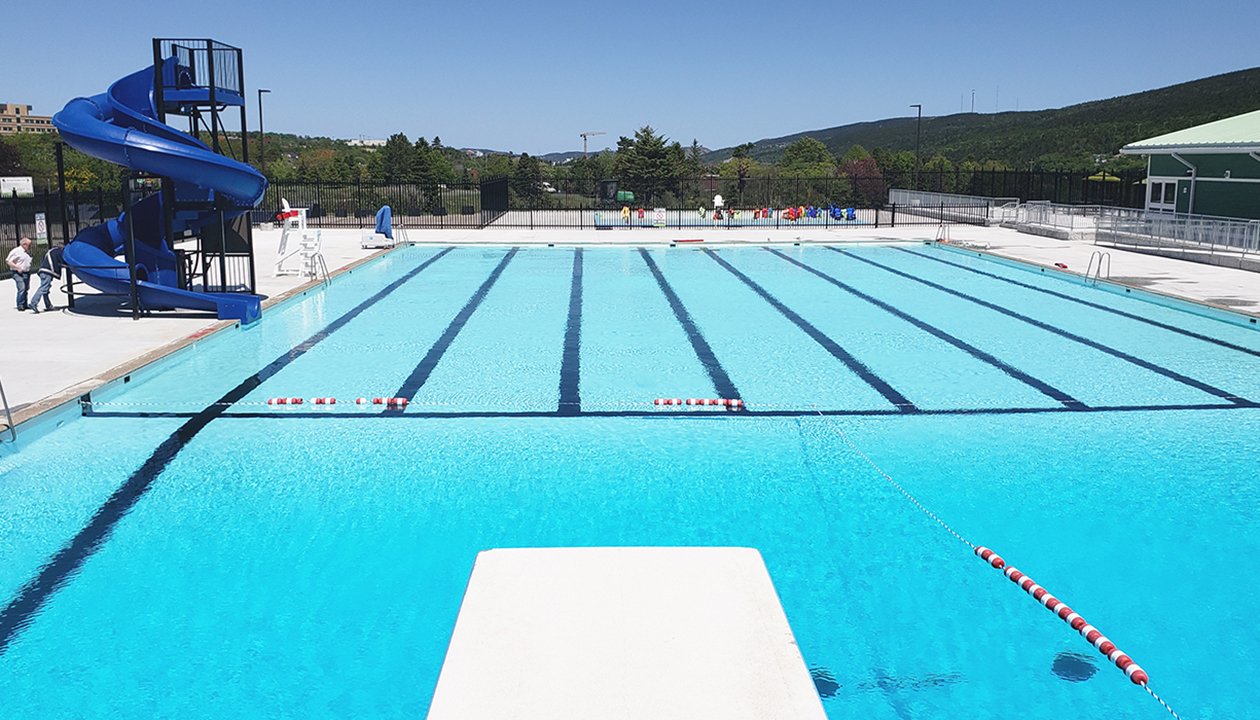 The Bowring Park swimming pool from the diving board with the water slide located on the left side and the pool house located on the right side