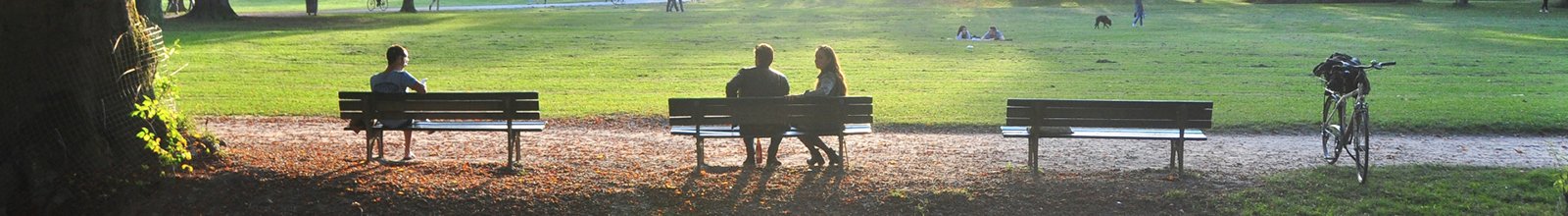 People sitting on park benches and a bicycle