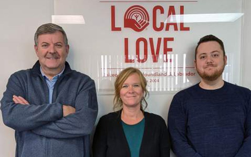 Photo of three people presenting a large cheque