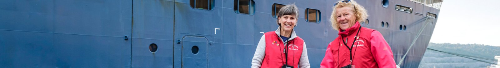 Two volunteers smiling by a ship
