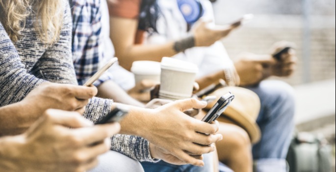 close cropped image of a group of individuals holding cell phones, shown from neck to knees