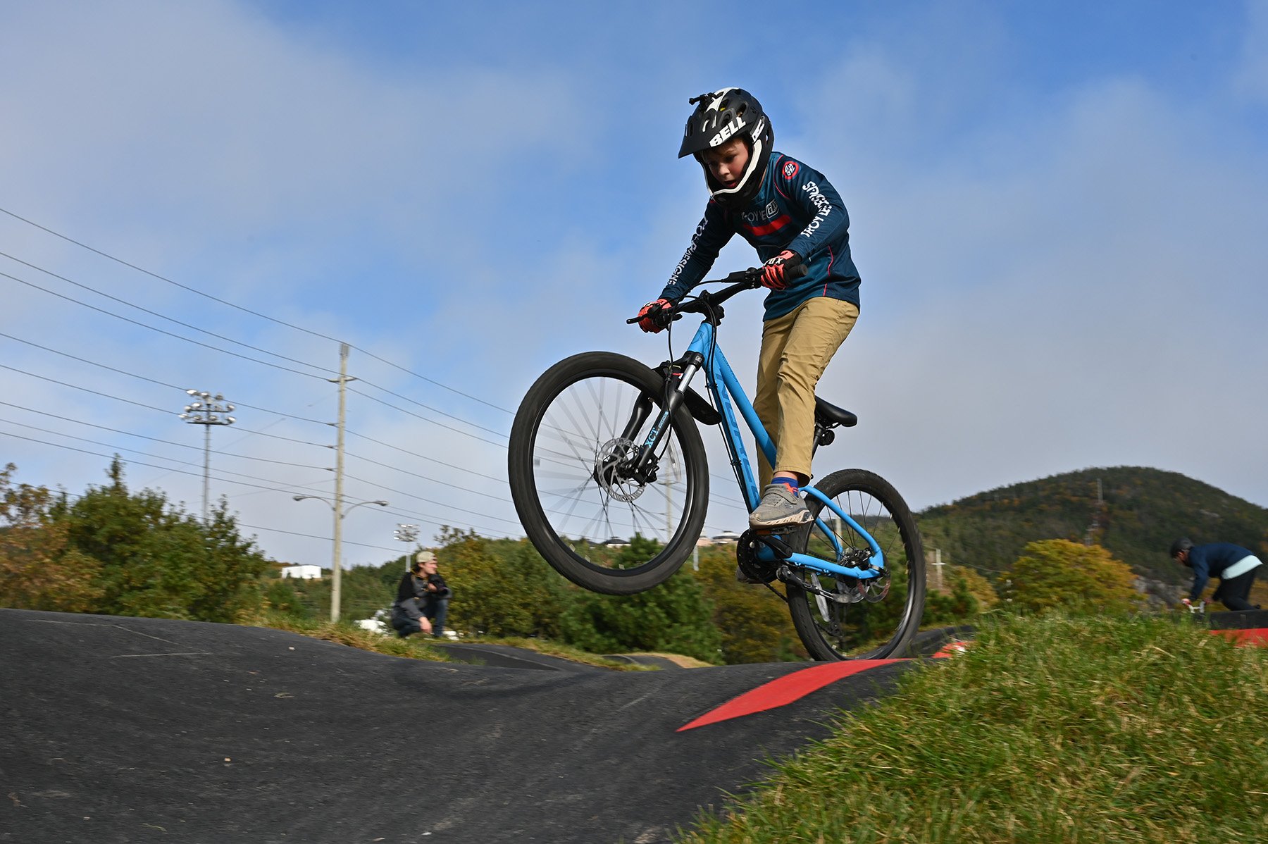 biker riding on the pump track above lens of camera against a blue sky