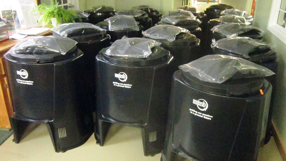 numerous large black compost bins are stacked in a building