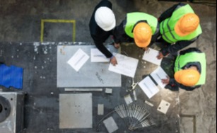 Overhead view of worktable with four people wearing hard hats looking at a plan