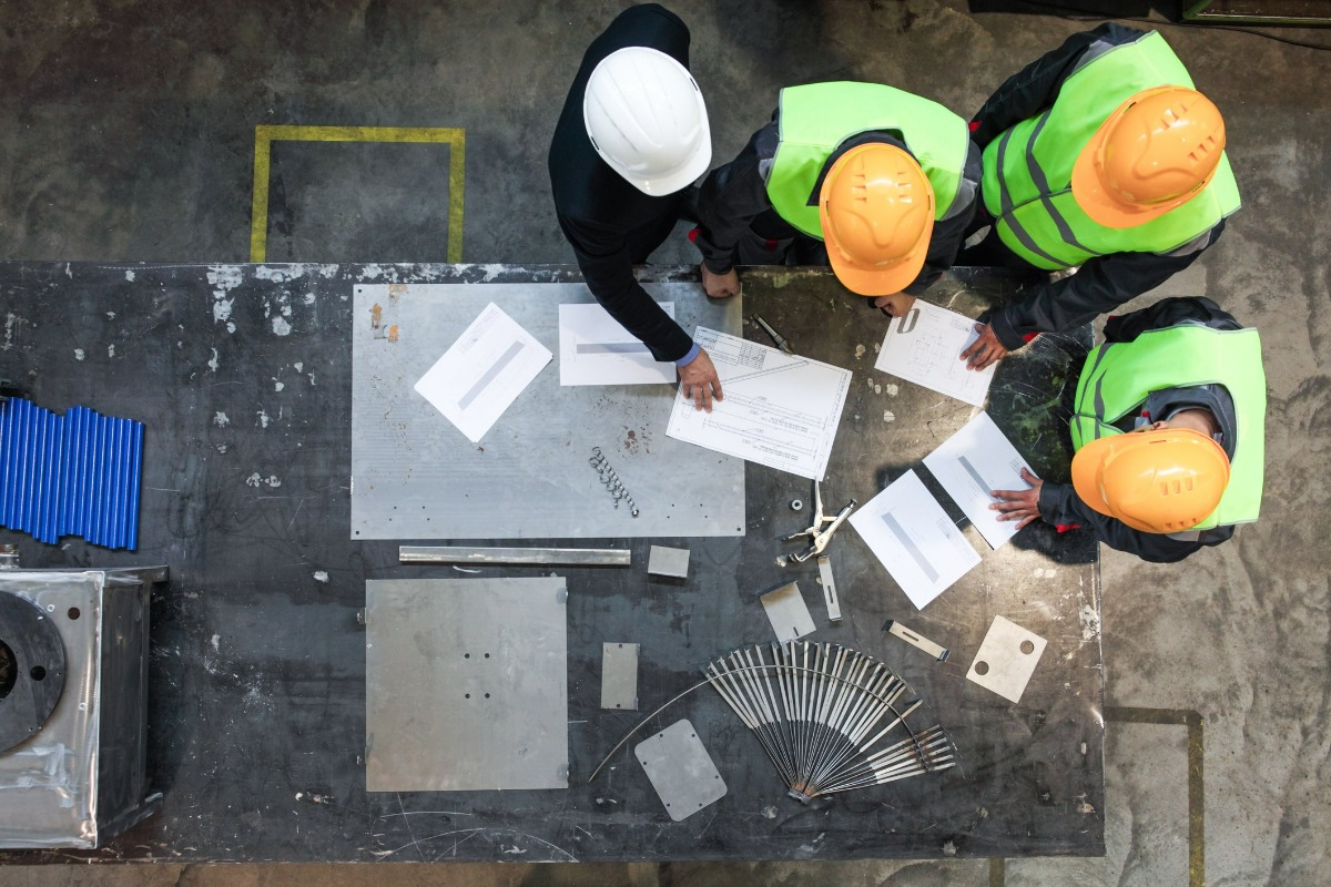 Shot from above with a worktable and four individuals wearing hard hats viewing a plan