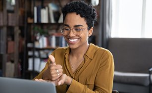 A person sitting in front of a computer screen communicating with sign language with the text Help Us Build a More Accessible City overlaid a blue background.
