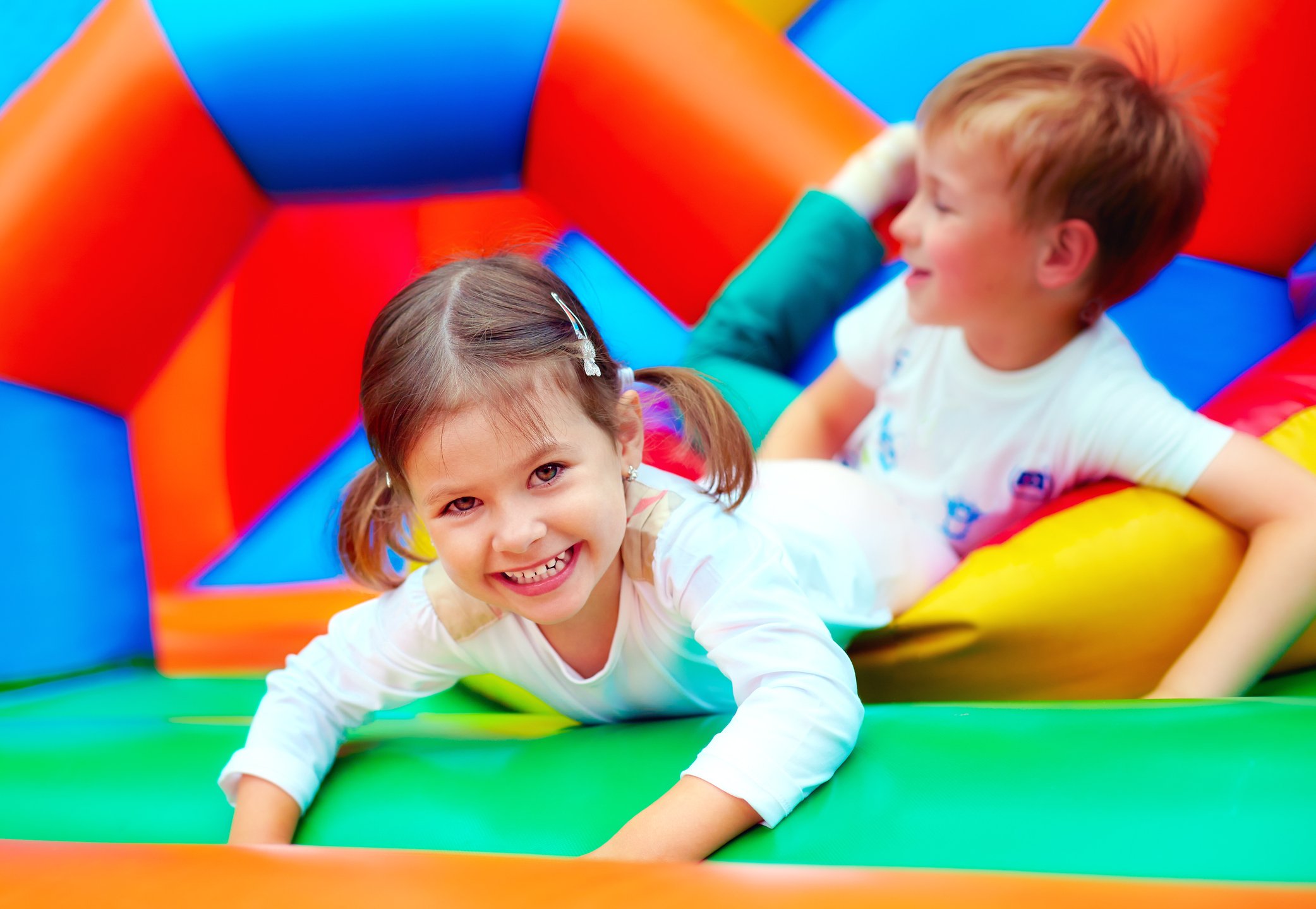 Two children playing in a colourful bouncy castle.
