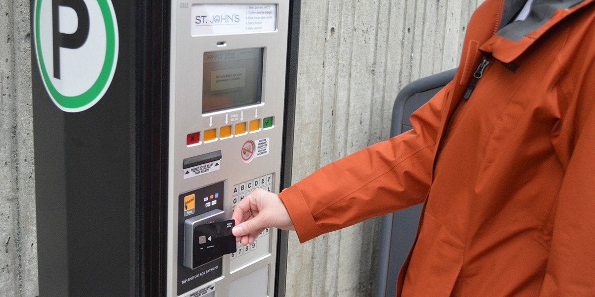 Person inserting payment into a parking pay station. 