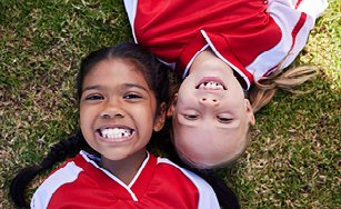 children lying in the grass and smiling. 