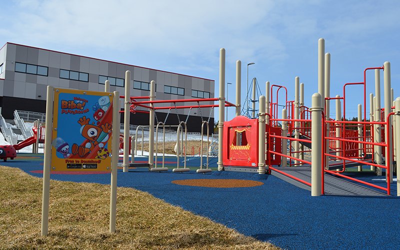 Photo of Kenmount Terrace Park playground equipment with the Community Centre in the background