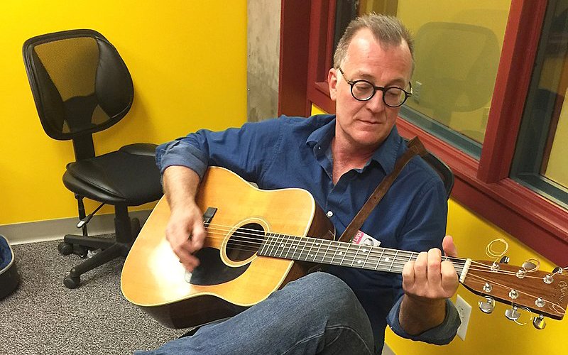 Photo of Darrell Power playing an acoustic guitar while sitting