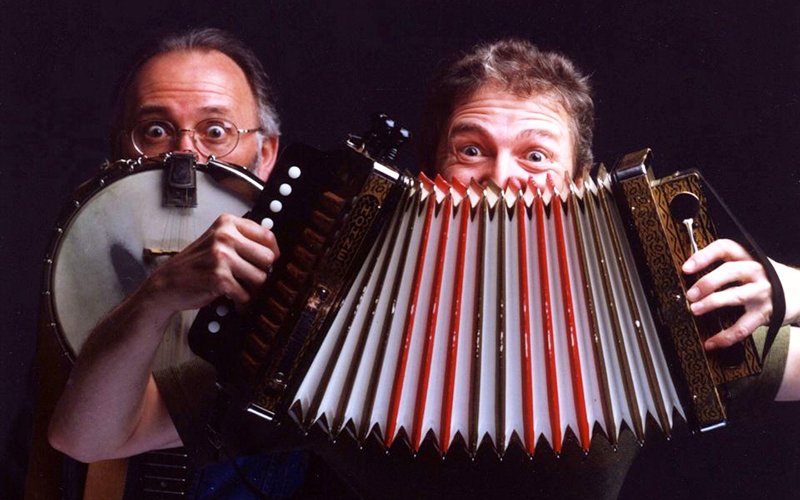 Photo of Fergus O'Byrne and Jim Payne peeking out from behind a banjo and an accordion