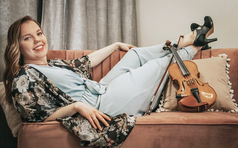 Photo of Rosemary Lawton lying on a couch with a violin near her feet