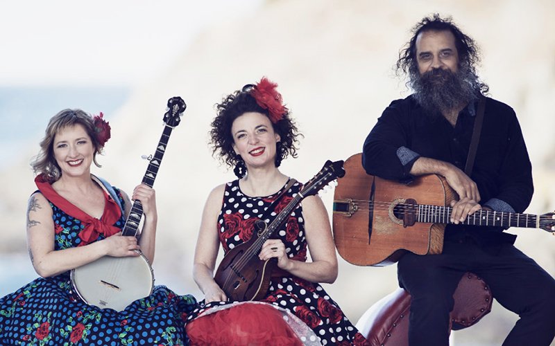 Photo of two women at left and a man right all holding stringed instruments
