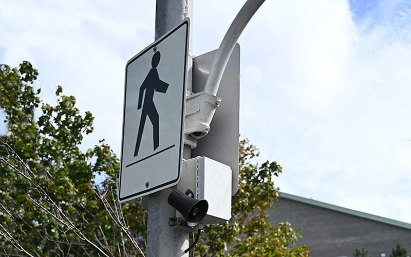A speaker for audible traffic signals mounted to a pole beside a crosswalk