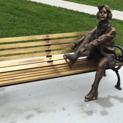 a statue of a person lacing up skates sitting on a bench