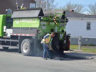 employee repairing pothole