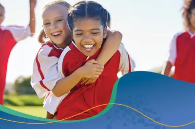 Young girls playing soccer and two are hugging