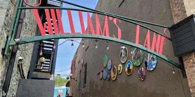 sign saying "William's Lane" with a mural in the foreground
