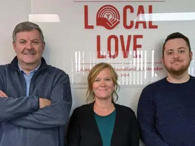 Three people standing in front of a sign that says "Local Love"