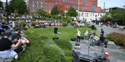 Music @ Harbourside Park event with people sitting and watching artist