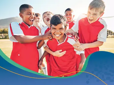 Young soccer players smiling and hugging a teammate 
